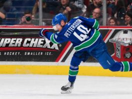 Elias Pettersson Trade Rumors: Is the Door Back Open for the Los Angeles Kings? Elias Pettersson of the Vancouver Canucks takes a powerful shot in action as a Super Chexx bubble hockey board ad appears behind him amid Los Angeles Kings trade rumors.