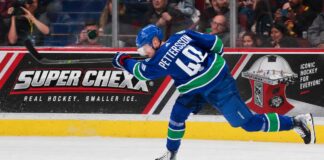 Elias Pettersson Trade Rumors: Is the Door Back Open for the Los Angeles Kings? Elias Pettersson of the Vancouver Canucks takes a powerful shot in action as a Super Chexx bubble hockey board ad appears behind him amid Los Angeles Kings trade rumors.
