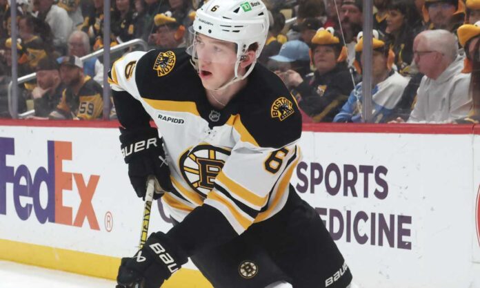 Mason Lohrei trade rumors Boston Bruins defenseman skating with the puck during NHL game action as Boston Bruins trade rumors heat up before training camp