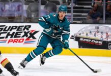 Michael Misa Point Projections 2026-27: San Jose Sharks Fantasy Outlook Michael Misa skating for the San Jose Sharks beside a Super Chexx Pro bubble hockey board ad in a 2026-27 fantasy hockey point projection.