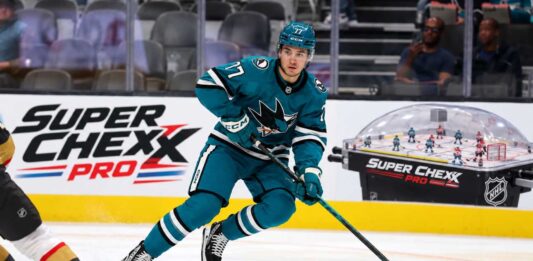 Michael Misa skating for the San Jose Sharks beside a Super Chexx Pro bubble hockey board ad in a 2026-27 fantasy hockey point projection.