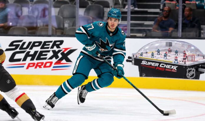 michael-misa-san-jose-sharks-fantasy-hockey-projection-2026-27 Michael Misa skating for the San Jose Sharks beside a Super Chexx Pro bubble hockey board ad in a 2026-27 fantasy hockey point projection.