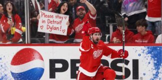 NHL News and NHL Rumors Today: Trade Buzz, Injuries and NHL Scores – September 26, 2026 Detroit Red Wings captain Dylan Larkin celebrates on one knee in front of cheering fans, including a female fan holding a “Please stay in Detroit Dylan!” sign, with a Pepsi board ad in the background.