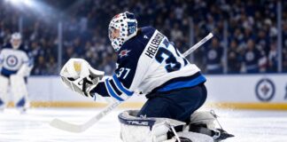 Connor Hellebuyck in Winnipeg Jets gear making a save during a game as NHL trade rumors and today’s NHL News spotlight his future