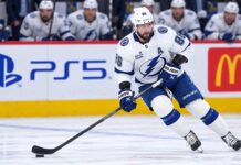 Tampa Bay Lightning star forward skating with the puck in a game action shot with PS5 and McDonald’s ads on the boards in the background