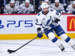 Tampa Bay Lightning star forward skating with the puck in a game action shot with PS5 and McDonald’s ads on the boards in the background