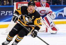 Sidney Crosby Trade Rumors: Did He Just Close the Door on a Canadiens or Avalanche Blockbuster? Sidney Crosby skating in a Pittsburgh Penguins home jersey with a Montreal Canadiens goalie in the background and a PS5 rink-board advertisement.