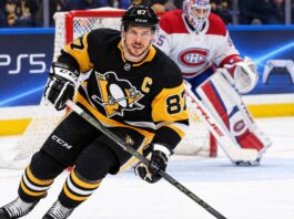 Sidney Crosby Trade Rumors: Did He Just Close the Door on a Canadiens or Avalanche Blockbuster? Sidney Crosby skating in a Pittsburgh Penguins home jersey with a Montreal Canadiens goalie in the background and a PS5 rink-board advertisement.