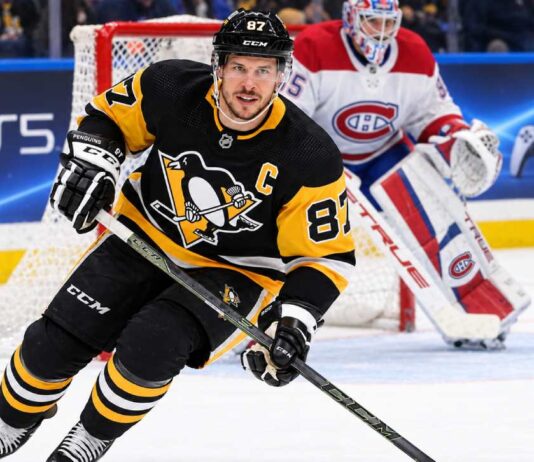 Sidney Crosby Trade Rumors: Did He Just Close the Door on a Canadiens or Avalanche Blockbuster? Sidney Crosby skating in a Pittsburgh Penguins home jersey with a Montreal Canadiens goalie in the background and a PS5 rink-board advertisement.