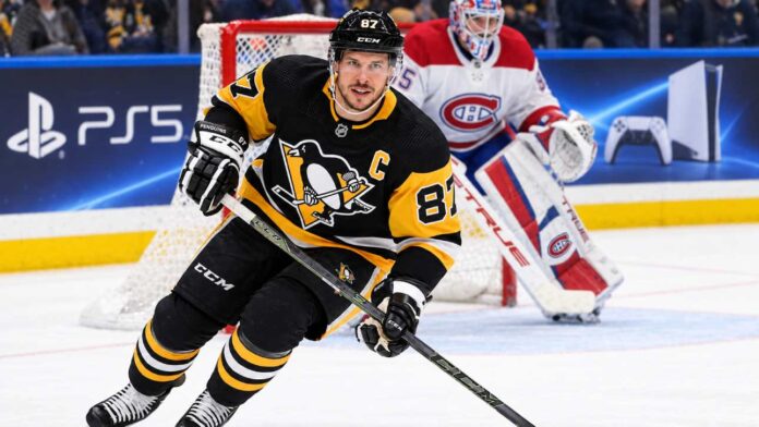 sidney-crosby-penguins-canadiens-avalanche-trade-rumors Sidney Crosby skating in a Pittsburgh Penguins home jersey with a Montreal Canadiens goalie in the background and a PS5 rink-board advertisement.