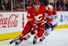Zach Whitecloud Trade Rumors: Are the Canadiens Quietly Circling Calgary’s Most Valuable Trade Chip? Zach Whitecloud of the Calgary Flames battles a Montreal Canadiens player as trade rumors link Whitecloud to Montreal.