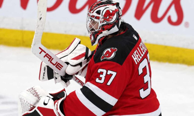 Connor Hellebuyck wearing a New Jersey Devils home jersey, red and black goalie equipment and Devils-themed mask in an edited image illustrating his blockbuster trade from the Winnipeg Jets in October 2026.