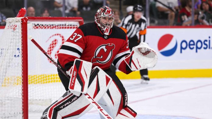 connor-hellebuycks-jets-trade-2026 Connor Hellebuyck wearing a New Jersey Devils home jersey and red, black and white goalie equipment following his blockbuster NHL trade from the Winnipeg Jets on October 23, 2026.