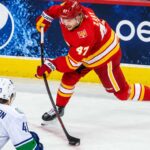 Canucks Eye Connor Zary After 31 NHL Teams Passed — What Does Vancouver See? Calgary Flames forward Connor Zary (#47) skating with the puck against Vancouver Canucks Elias Pettersson in an away jersey, with a Pepsi advertisement on the boards, amid NHL trade rumors linking Zary to Vancouver.