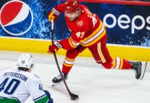 Canucks Eye Connor Zary After 31 NHL Teams Passed — What Does Vancouver See? Calgary Flames forward Connor Zary (#47) skating with the puck against Vancouver Canucks Elias Pettersson in an away jersey, with a Pepsi advertisement on the boards, amid NHL trade rumors linking Zary to Vancouver.