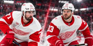 Dylan Larkin and Alex DeBrincat in Detroit Red Wings jerseys as DeBrincat's $91 million contract extension raises questions about Larkin's future amid NHL trade rumors.