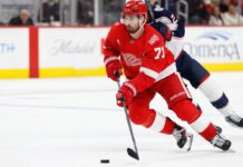Dylan Larkin Trade Rumors: Did Detroit’s Wild Scouting Trips Change Everything? Dylan Larkin of the Detroit Red Wings wearing his red No. 71 jersey and helmet, skating with the puck amid NHL trade rumors linking him to the Minnesota Wild.