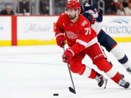 Dylan Larkin of the Detroit Red Wings wearing his red No. 71 jersey and helmet, skating with the puck amid NHL trade rumors linking him to the Minnesota Wild.