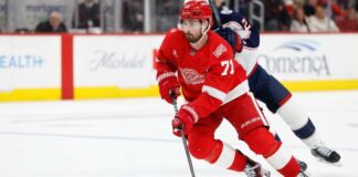 Dylan Larkin of the Detroit Red Wings wearing his red No. 71 jersey and helmet, skating with the puck amid NHL trade rumors linking him to the Minnesota Wild.