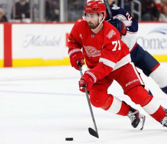 Dylan Larkin of the Detroit Red Wings wearing his red No. 71 jersey and helmet, skating with the puck amid NHL trade rumors linking him to the Minnesota Wild.