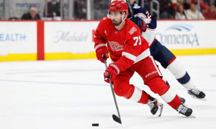Dylan Larkin of the Detroit Red Wings wearing his red No. 71 jersey and helmet, skating with the puck amid NHL trade rumors linking him to the Minnesota Wild.