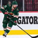 Dylan Larkin Trade Rumors: Did Detroit’s Latest Scouting Trip Reveal Its Next Move? Dylan Larkin wearing a Minnesota Wild home jersey in a trade rumor concept image as the Detroit Red Wings reportedly scout Minnesota ahead of a potential NHL blockbuster.