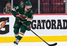 Dylan Larkin Trade Rumors: Did Detroit’s Latest Scouting Trip Reveal Its Next Move? Dylan Larkin wearing a Minnesota Wild home jersey in a trade rumor concept image as the Detroit Red Wings reportedly scout Minnesota ahead of a potential NHL blockbuster.