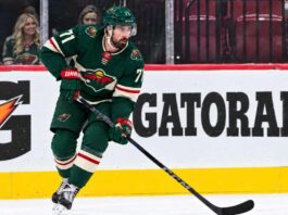 Dylan Larkin wearing a Minnesota Wild home jersey in a trade rumor concept image as the Detroit Red Wings reportedly scout Minnesota ahead of a potential NHL blockbuster.