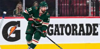 Dylan Larkin wearing a Minnesota Wild home jersey in a trade rumor concept image as the Detroit Red Wings reportedly scout Minnesota ahead of a potential NHL blockbuster.