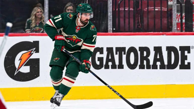 Dylan Larkin wearing a Minnesota Wild home jersey in a trade rumor concept image as the Detroit Red Wings reportedly scout Minnesota ahead of a potential NHL blockbuster.