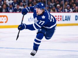 Simon Edvinsson wearing a Toronto Maple Leafs home jersey in a concept image, skating in front of Leafs fans amid NHL trade rumors involving the Detroit Red Wings.