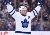 Morgan Rielly wearing a white Toronto Maple Leafs away jersey and helmet as NHL trade rumors intensify following reports that the Leafs struggled to find a trade partner for the veteran defenseman.