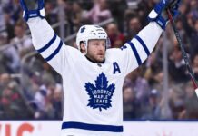 Maple Leafs Tried to Trade Morgan Rielly: Insider Reveals Why Nobody Bit Morgan Rielly wearing a white Toronto Maple Leafs away jersey and helmet as NHL trade rumors intensify following reports that the Leafs struggled to find a trade partner for the veteran defenseman.