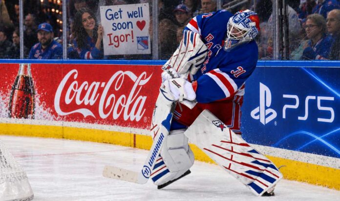nhl-news-rumors-scores-october-10-2026 New York Rangers goalie Igor Shesterkin in action as a female Rangers fan holds a "Get well soon Igor!" sign behind the glass, following his season-ending injury. Coca-Cola and PS5 advertisements line the boards.