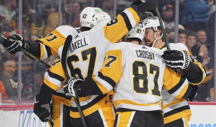 Pittsburgh Penguins forwards Rickard Rakell (67) and Sidney Crosby (87) celebrate with teammates during an NHL game amid Penguins trade rumors involving Kyle Dubas, Erik Karlsson, Kris Letang and Bryan Rust.
