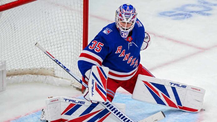 sam-montembeault-new-york-rangers-montreal-canadiens-trade-rumors Sam Montembeault wearing a New York Rangers home jersey and goalie equipment in a mock trade image highlighting NHL trade rumors involving the Montreal Canadiens.