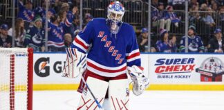 New York Rangers goalie Igor Shesterkin in front of his net with Gatorade and Super Chexx Bubble Hockey board ads and Canucks and Rangers fans in the stands.