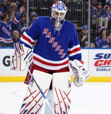 New York Rangers goalie Igor Shesterkin in front of his net with Gatorade and Super Chexx Bubble Hockey board ads and Canucks and Rangers fans in the stands.