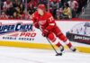 Simon Edvinsson Trade Rumors: Has Detroit Lost Another Core Piece? Simon Edvinsson skates for the Detroit Red Wings beside a Super Chexx Pro Bubble Hockey ad amid NHL trade rumors.