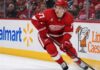 Simon Edvinsson Trade Rumors: Did the Flyers’ Nightmare Start Just Accelerate a Blockbuster? Simon Edvinsson skating for the Detroit Red Wings amid Philadelphia Flyers trade rumors, with Walmart and Little Caesars ads on the boards.