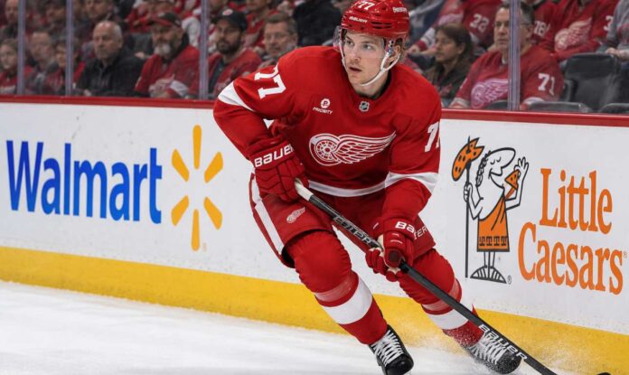 simon-edvinsson-flyers-trade-rumors-red-wings Simon Edvinsson skating for the Detroit Red Wings amid Philadelphia Flyers trade rumors, with Walmart and Little Caesars ads on the boards.