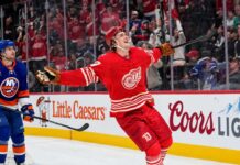 Simon Edvinsson of the Detroit Red Wings celebrates a goal beside New York Islanders defenseman Alexander Romanov as NHL trade rumors swirl around a potential $9 million Islanders offer sheet.