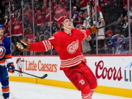 Simon Edvinsson of the Detroit Red Wings celebrates a goal beside New York Islanders defenseman Alexander Romanov as NHL trade rumors swirl around a potential $9 million Islanders offer sheet.