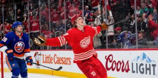 Simon Edvinsson of the Detroit Red Wings celebrates a goal beside New York Islanders defenseman Alexander Romanov as NHL trade rumors swirl around a potential $9 million Islanders offer sheet.