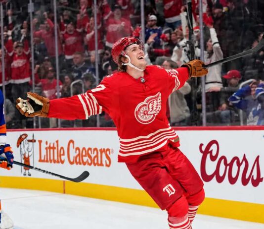 Simon Edvinsson of the Detroit Red Wings celebrates a goal beside New York Islanders defenseman Alexander Romanov as NHL trade rumors swirl around a potential $9 million Islanders offer sheet.