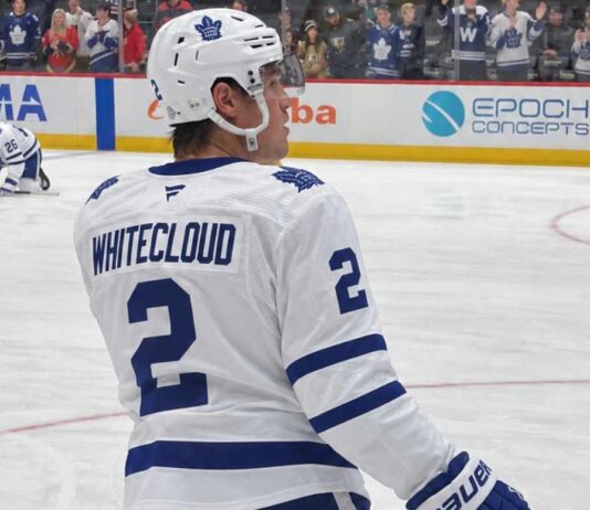 Zach Whitecloud pictured in a Toronto Maple Leafs white away jersey in a trade rumor photo illustration, as Toronto explores defensive upgrades involving the Calgary Flames blueliner.